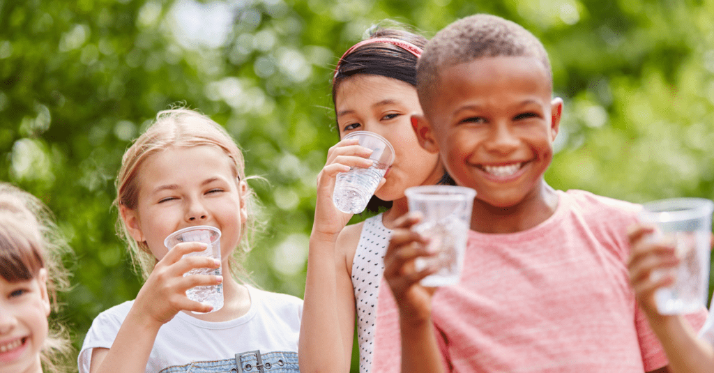 Group of youths smiling and drinking water in the summertime heat.