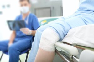Patient with treated knee injury sits in clinical setting with medical provider reading an X-ray
