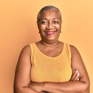 Beautiful older woman smiles confidently at the camera with her arms crossed
