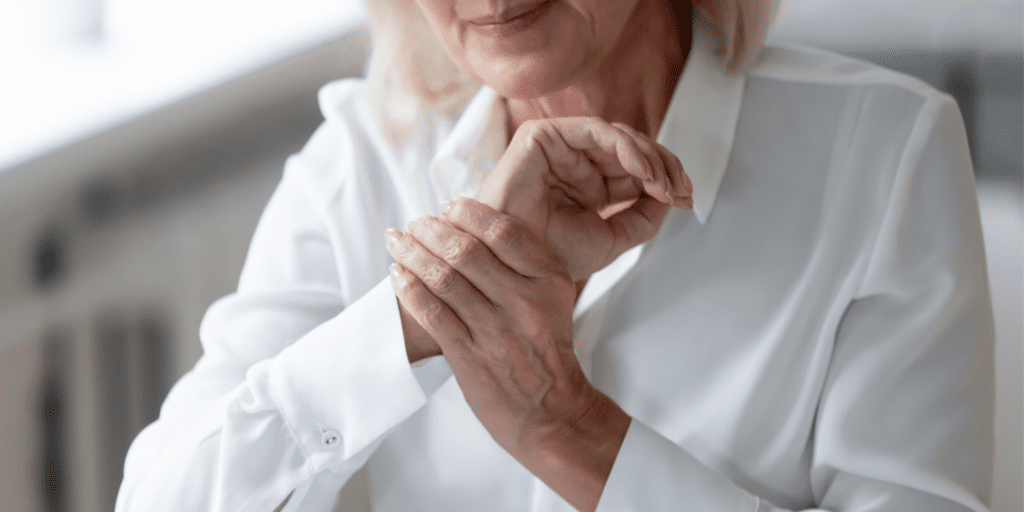 Senior woman holds her wrist in her hand looking as though she is in discomfort