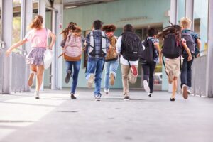 Group of youths at school run to class wearing their backpacks