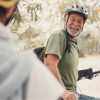 Happy senior wearing helmet looks back at fellow cyclist while enjoying a bike ride